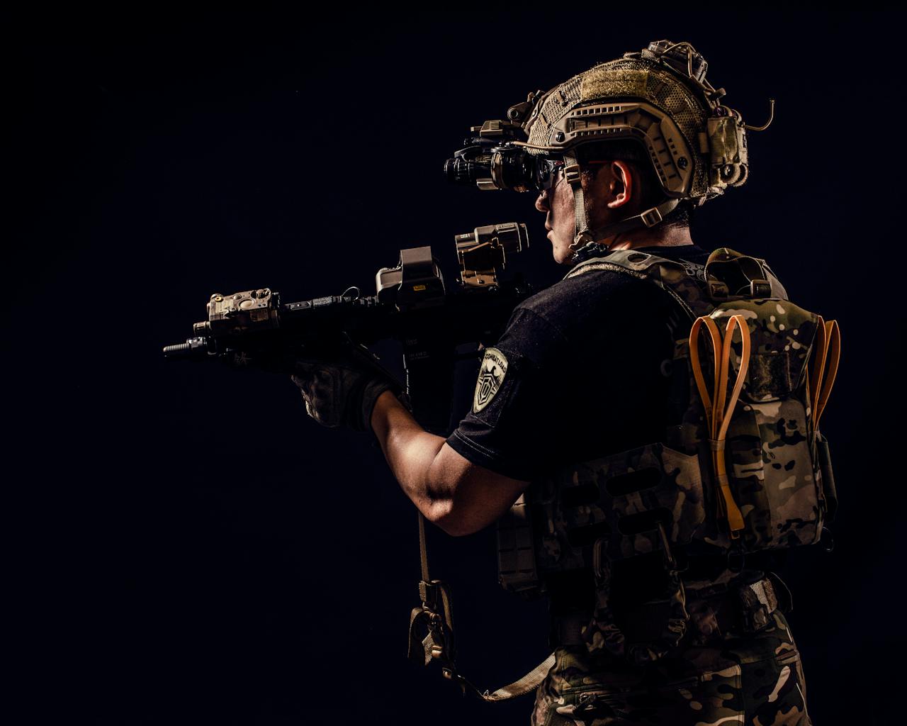 Portrait of a soldier in tactical gear holding a rifle in a studio setting.